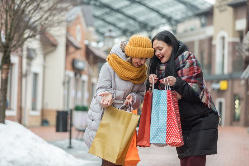 Two happy shoppers comparing purchases in shopping bags