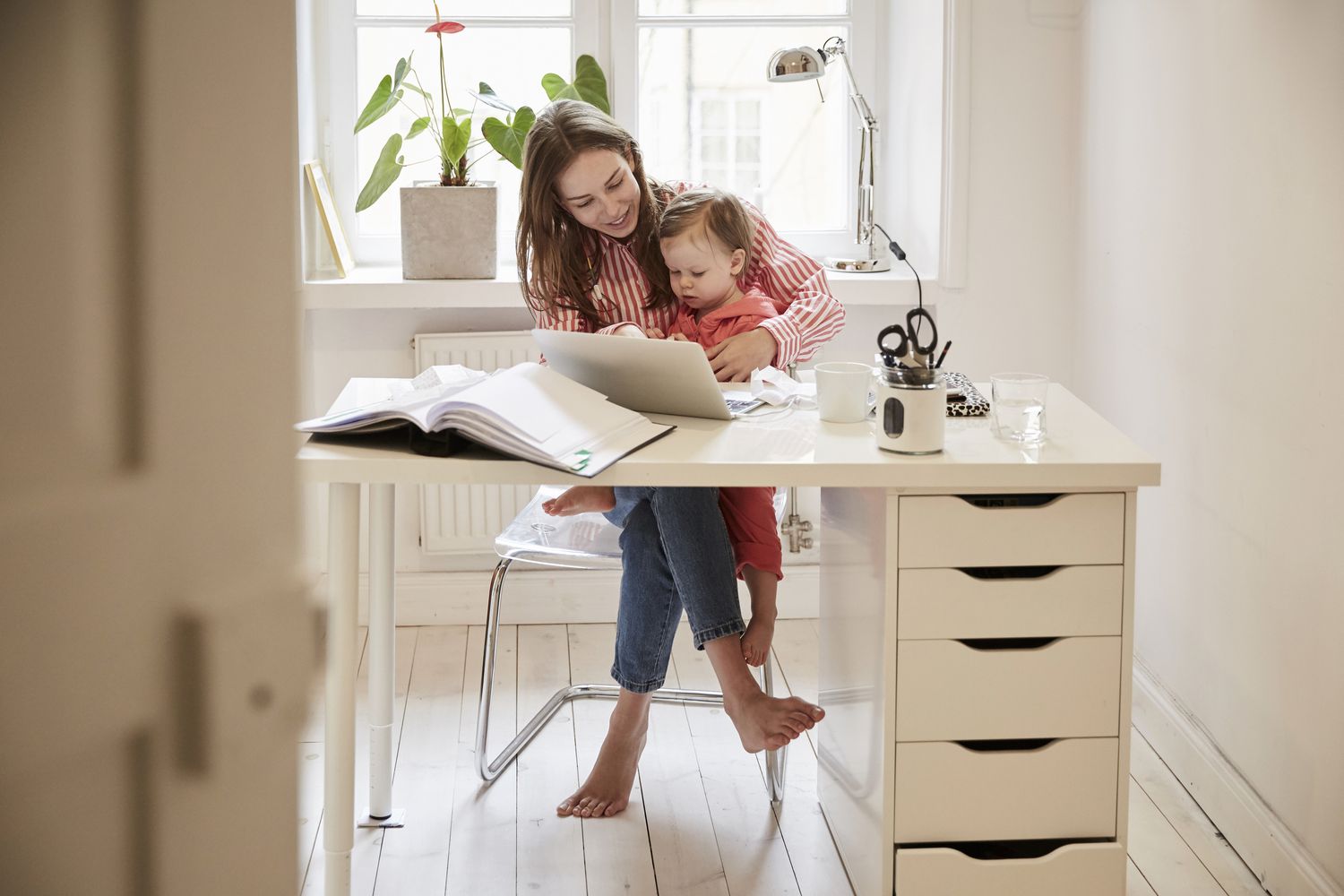 Mom holding baby on a chair while working out the payments for a variable rate mortgage.