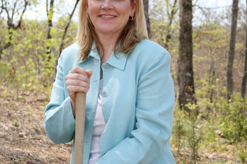 A well-dressed city official holds a shovel as they ceremonially break ground for a new shopping center which will broaden the city tax base.