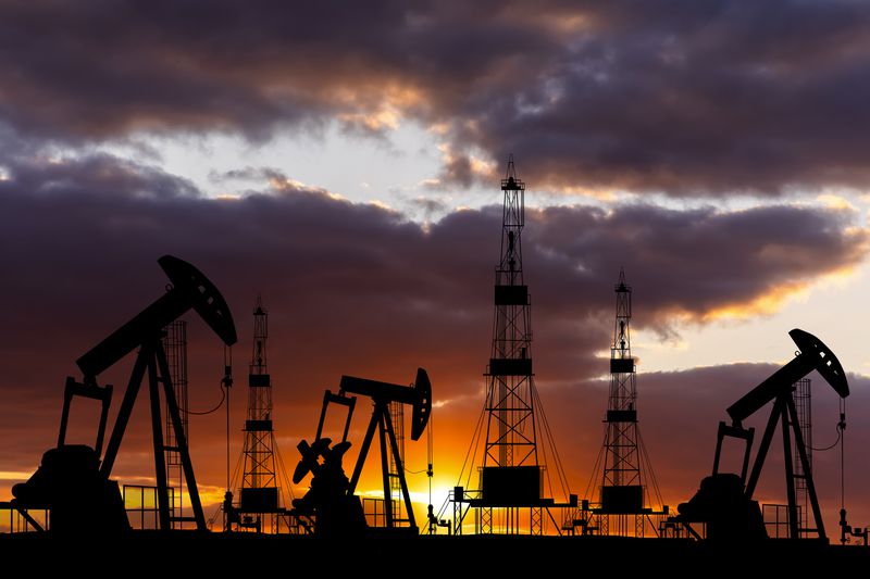 Oil field with rigs at sunset. 