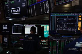 Traders working on a busy stock exchange floor surrounded by numerous monitors displaying financial data and stock information