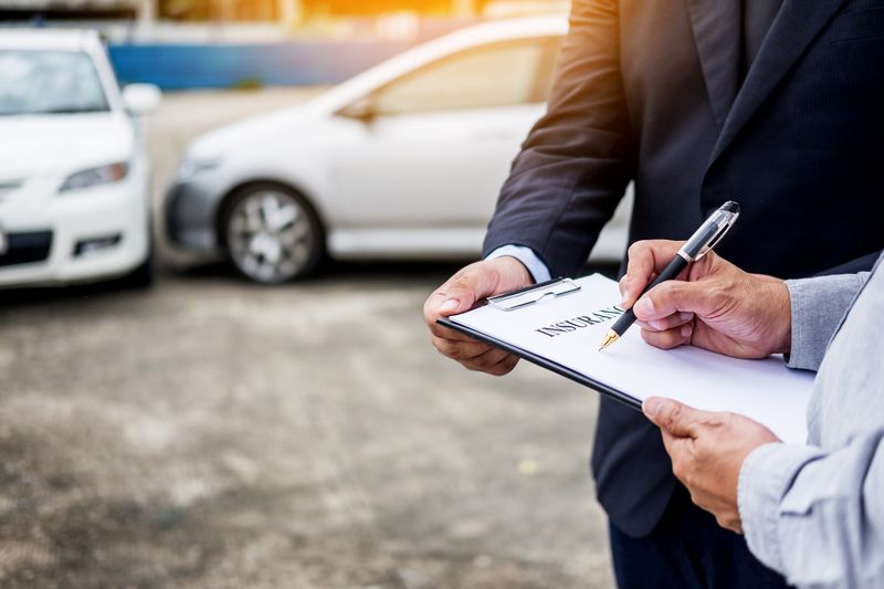 Midsection of Man Signing Car Insurance Form