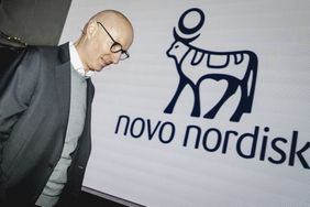 Novo Nordisk CEO Lars Fruergaard Jørgensen walks by a wall with the company's logo.