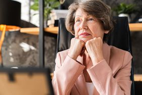 Older woman with her fisted hands on her chin, looking contemplative