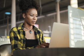 Woman sits on computer at a desk reading the Kraken review from Investopedia