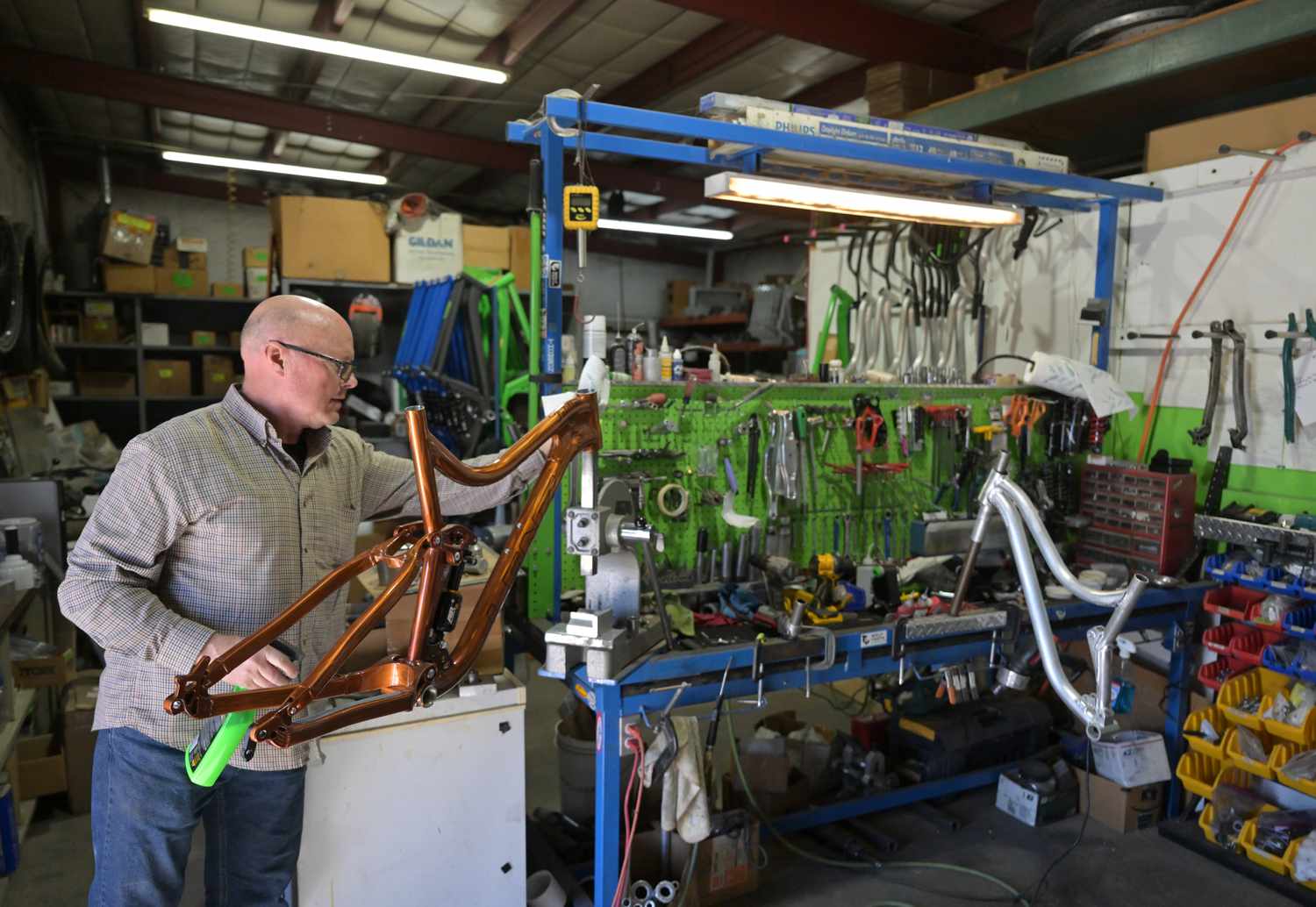 Devin Lenz cleans the frame of a custom full suspension mountain bike he is working on at his shop in Fort Lupton, Colorado on March 19, 2024.