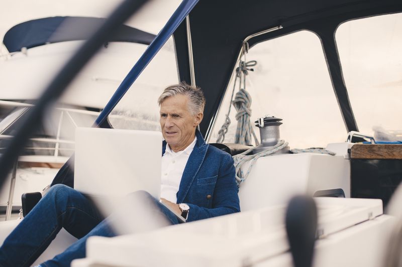 Man using a laptop while sitting on a boat. 