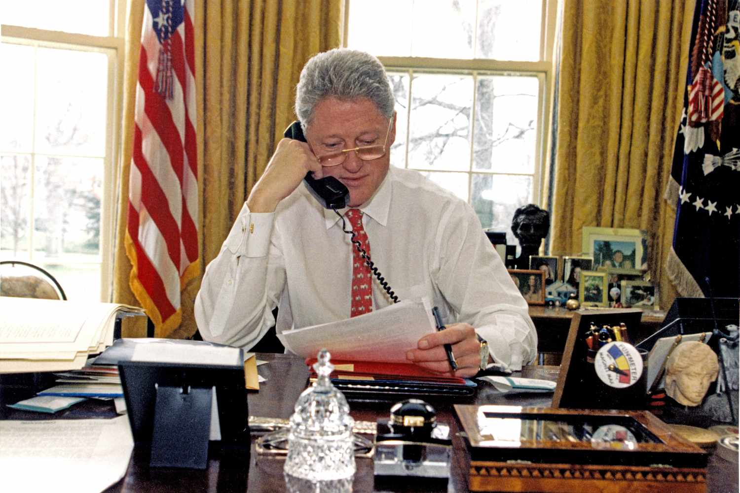 President Bill Clinton sits at their desk in the oval office and speaks on the phone to congressional members to rally support of the 1997 Taxpayer Relief Act.
