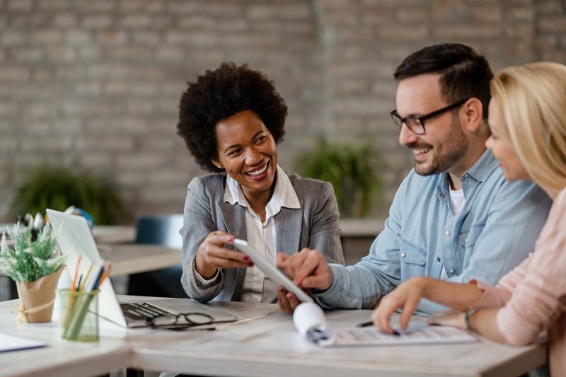 Insurance agent and a couple using touchpad in an office