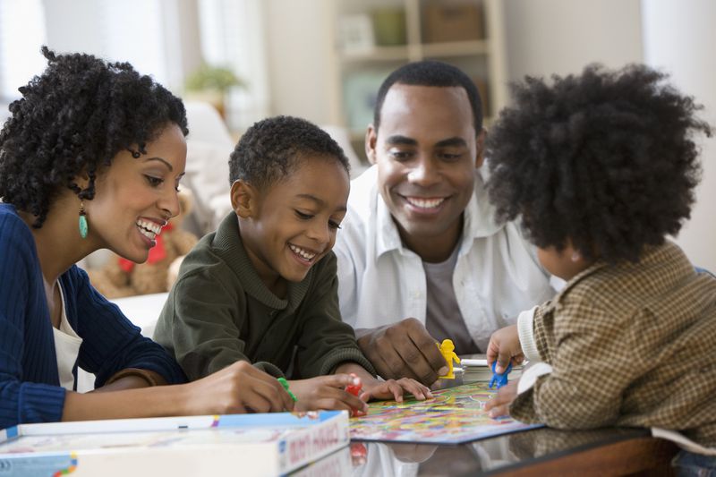 African American family playing board game together
