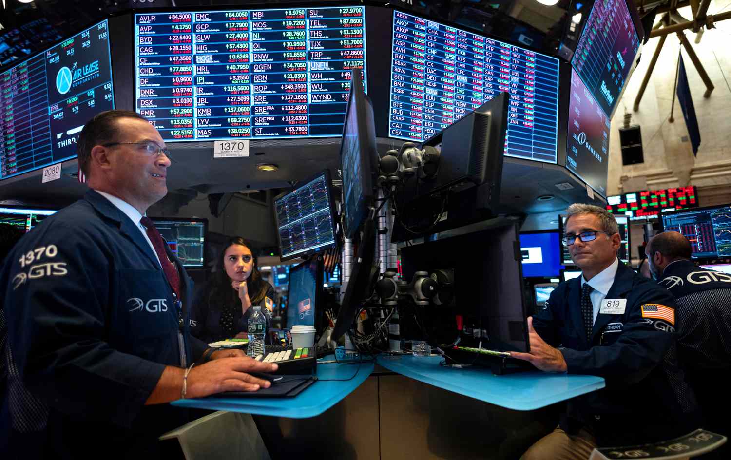 Two traders face computer screens while working at desks at the New York Stock Exchange.