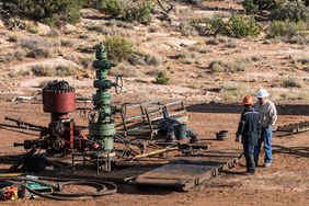 Service crew by a partially disassembled blowout preventer on an oil well head undergoing intervention..
