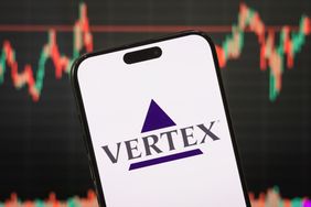 The logo of Vertex Pharmaceuticals Incorporated is displayed on a smartphone screen, with the company's stock market performance and candlestick chart visible in the background