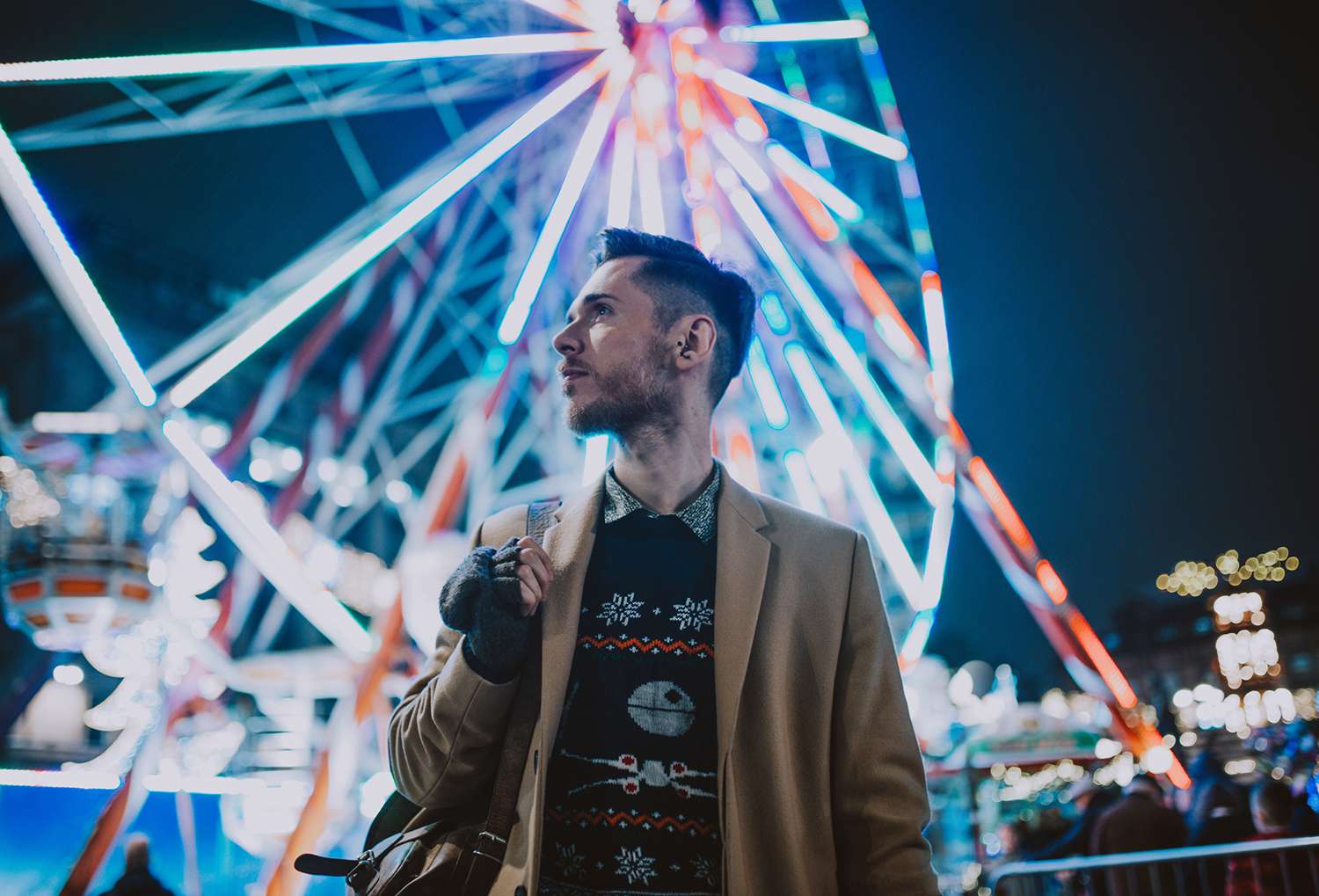 Stylish Young Man at a Carnival/Funfair Standing in Front of a Big Wheel