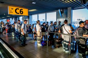 Travelers are seen waiting in departure halls to catch their flight from Schiphol airport in the Netherlands