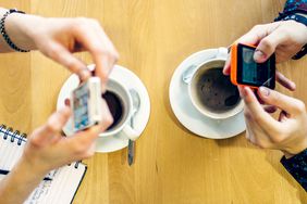Two people in a cafe sending a peer-to-peer money exchange via their iPhone smartphones