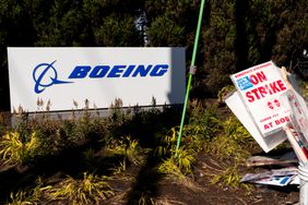 A pile of strike picket signs sit next to a Boeing sign.