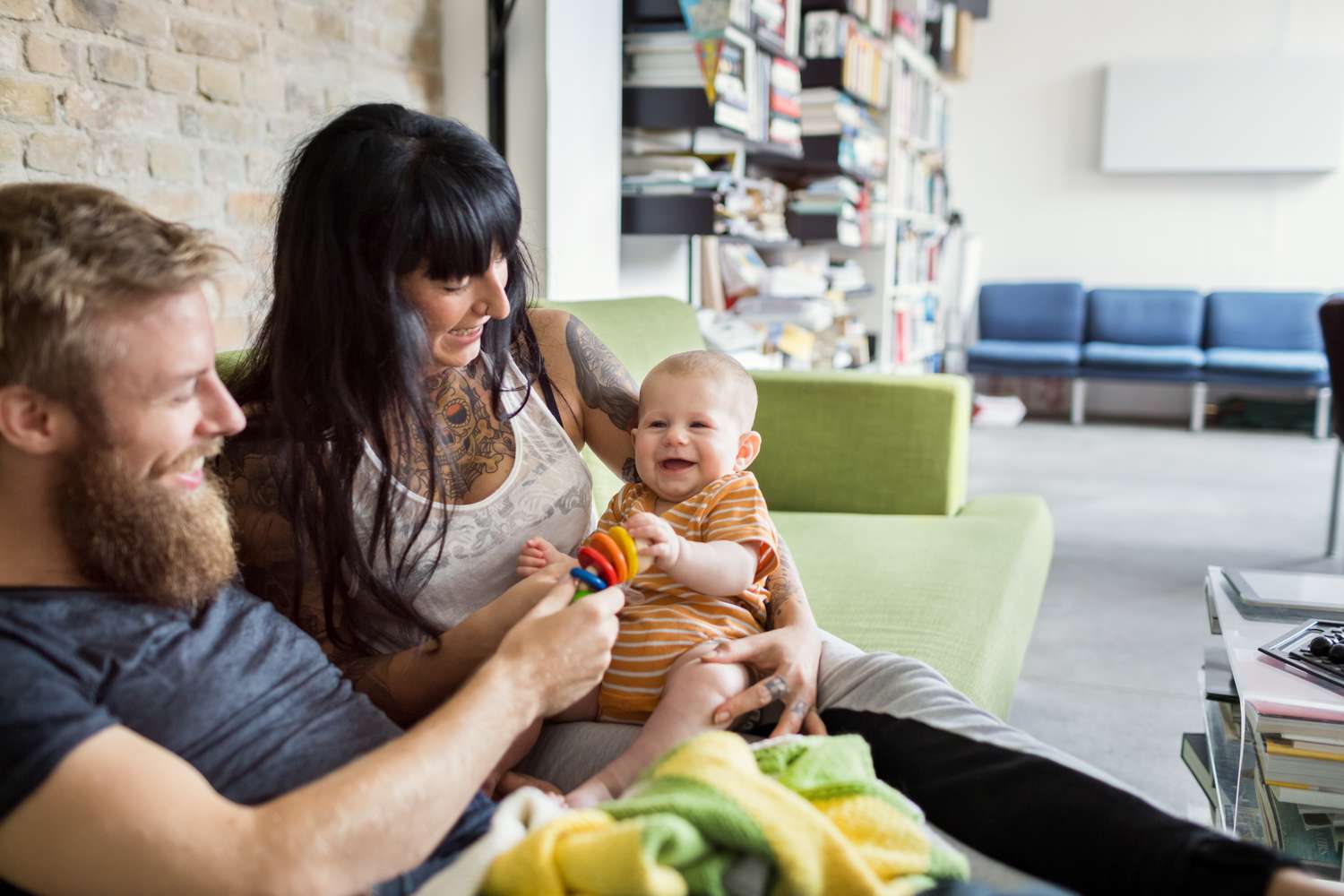 A young couple enjoy playtime with a smiling, happy infant
