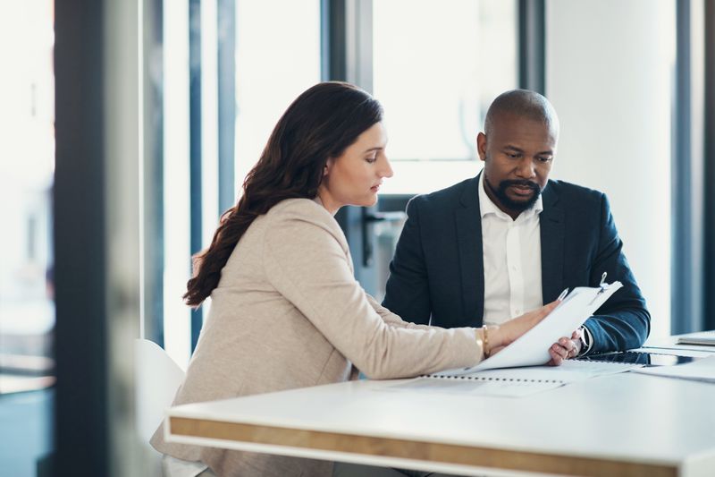A business owner and a banker sit at an office desk and discuss using investment securities as collateral for a loan.