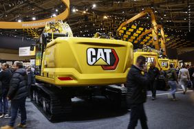People walk around Caterpillar construction vehicles in a convention center