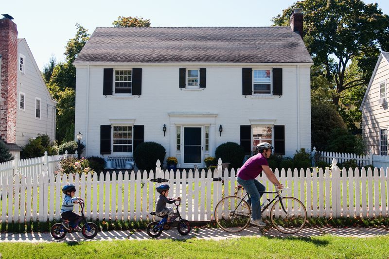 A family bikes in front of a home.