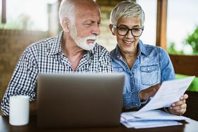 Mature couple reviewing investments on laptop at home.