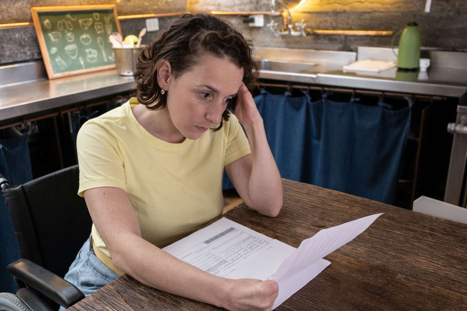 Woman looking at paper statements in a kitchen