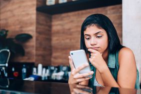 Teenager standing in the kitchen pondering over a Venmo request.
