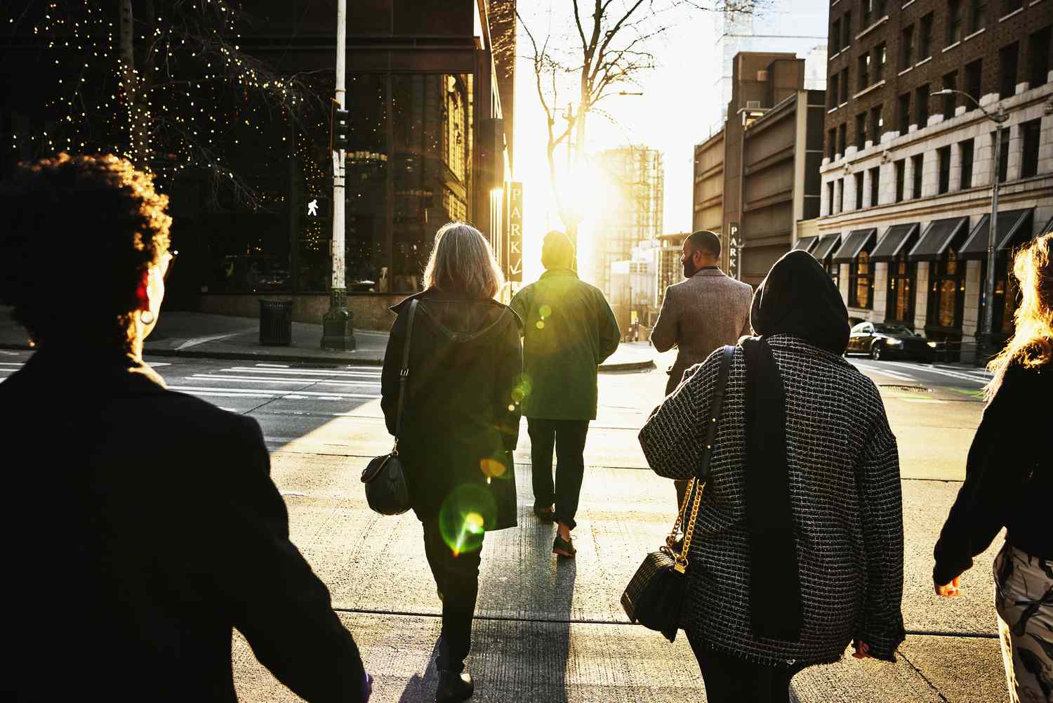Wide shot rear view of business people crossing downtown street during evening commute