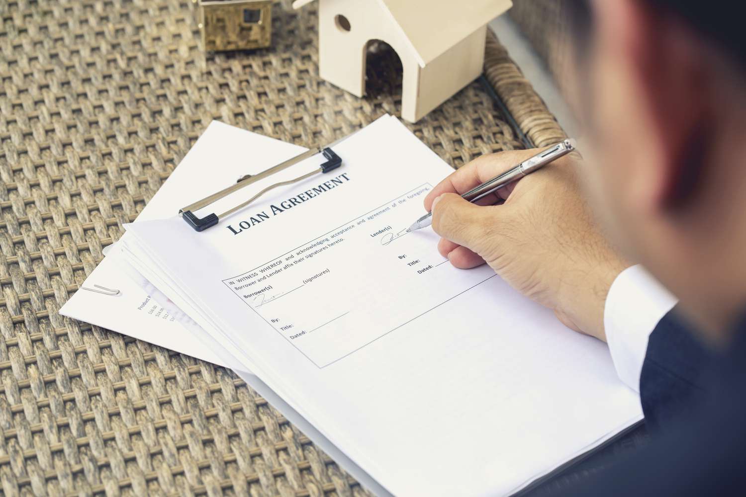 Loan officer signing as Lender with a pen on the loan agreement for a mortgage. 