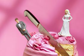 A cake with a bride and groom figurine, a knife cutting into the middle
