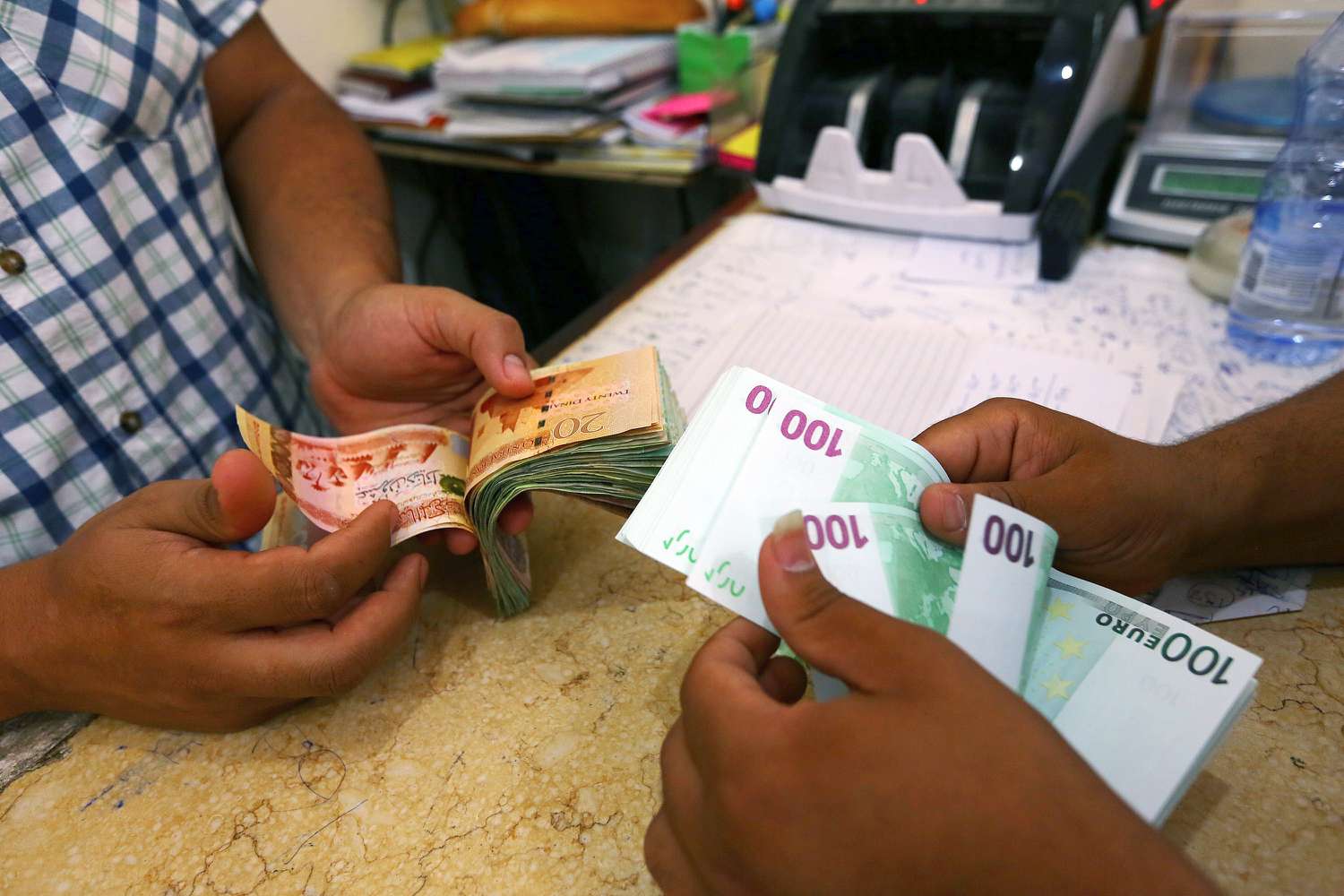Close up of hands exchanging bank notes at a currency exchange in Tripoli