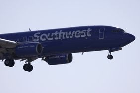 A blue Southwest Airlines plane is seen in the sky with its landing gear extended.