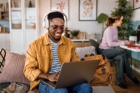 Young person uses laptop at a cafe and looks for online forex trading class.