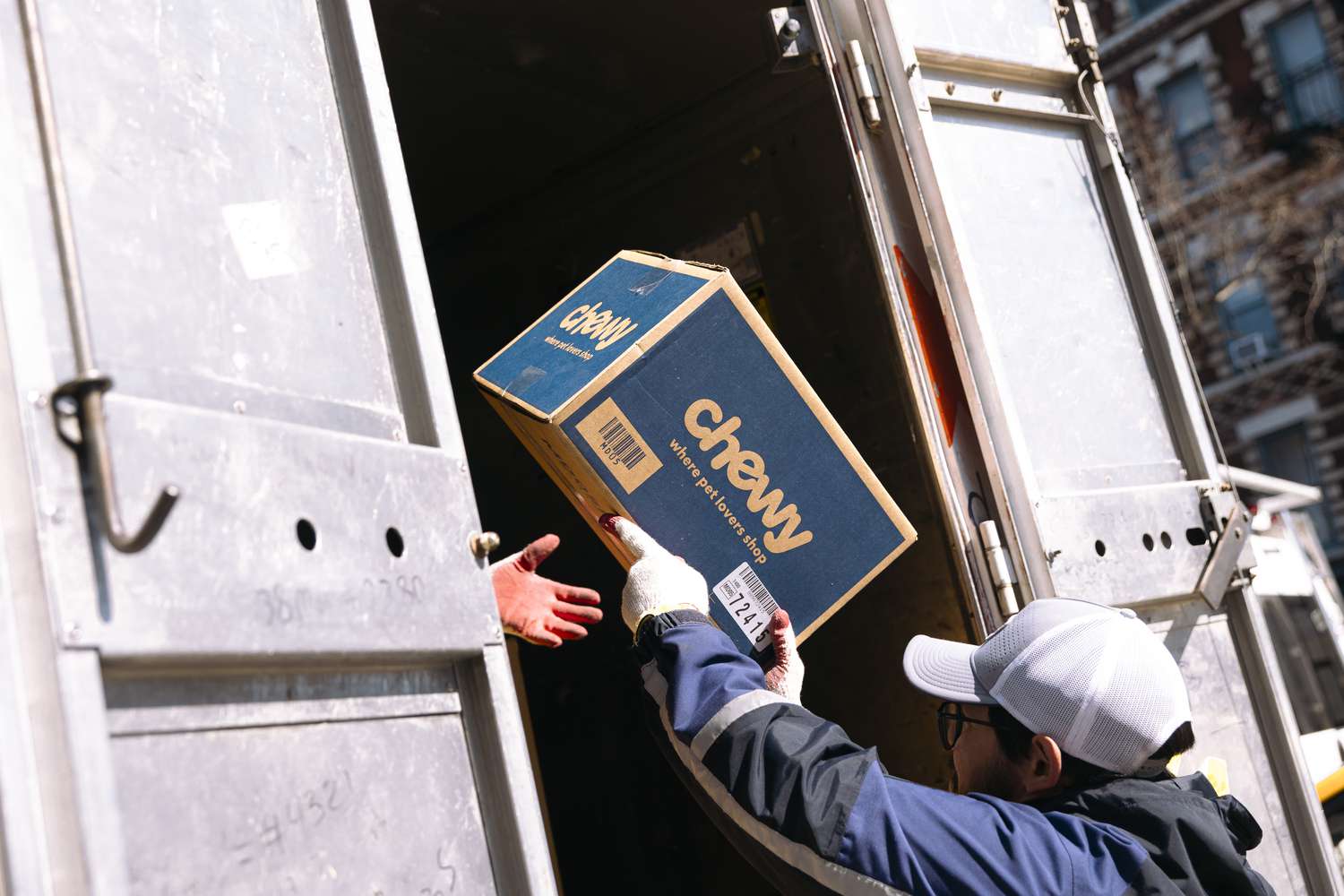 A worder unloads a Chewy box from a delivery vehicle in New York City 