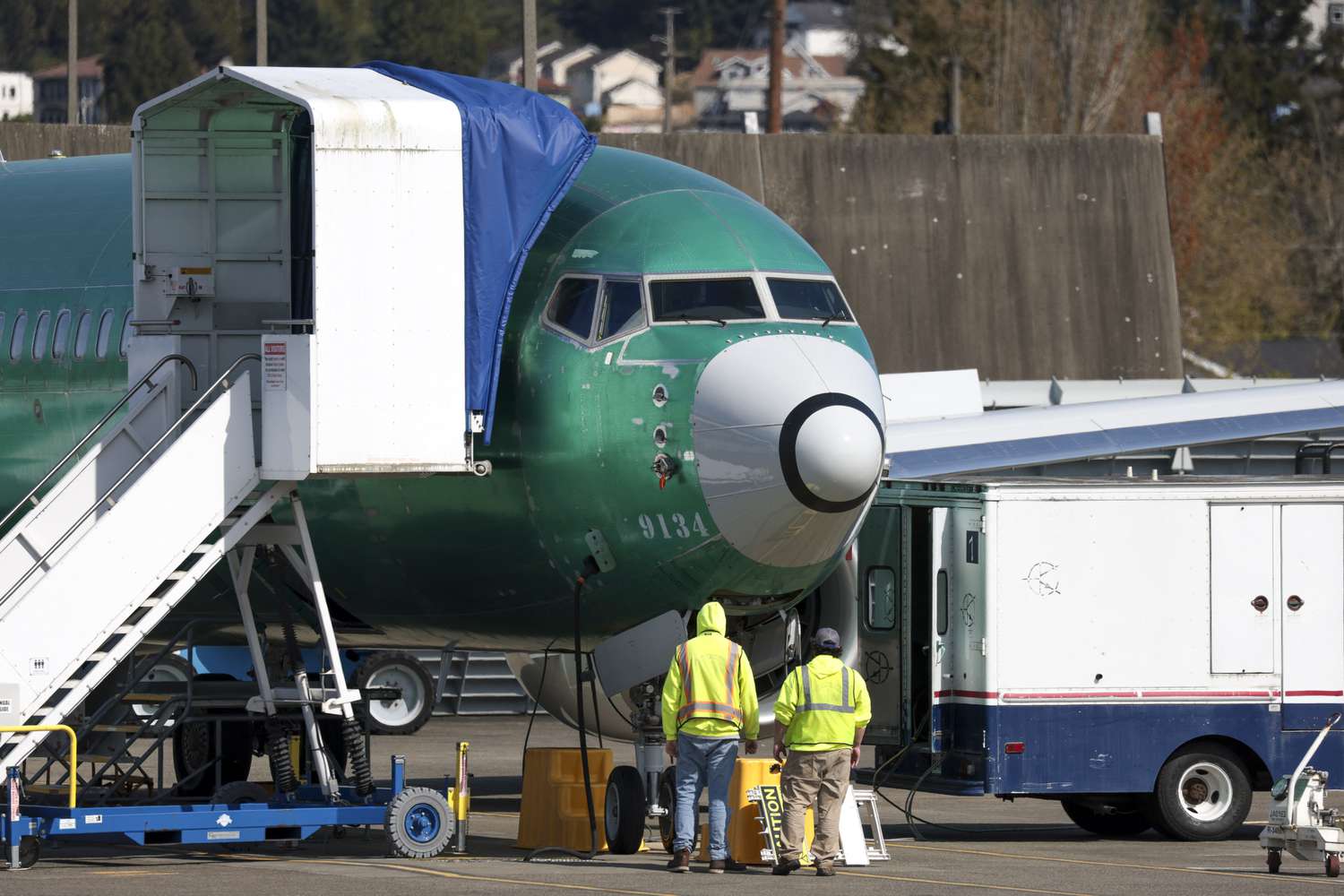 Workers stand in front of a Boeing 737 aircraft at Boeing's Renton factory in Renton, Washington, on April 15, 2025.