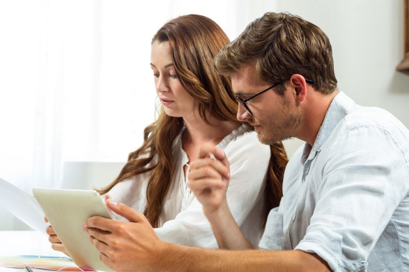 Young couple at home, looking together at bank interest rates on a tablet