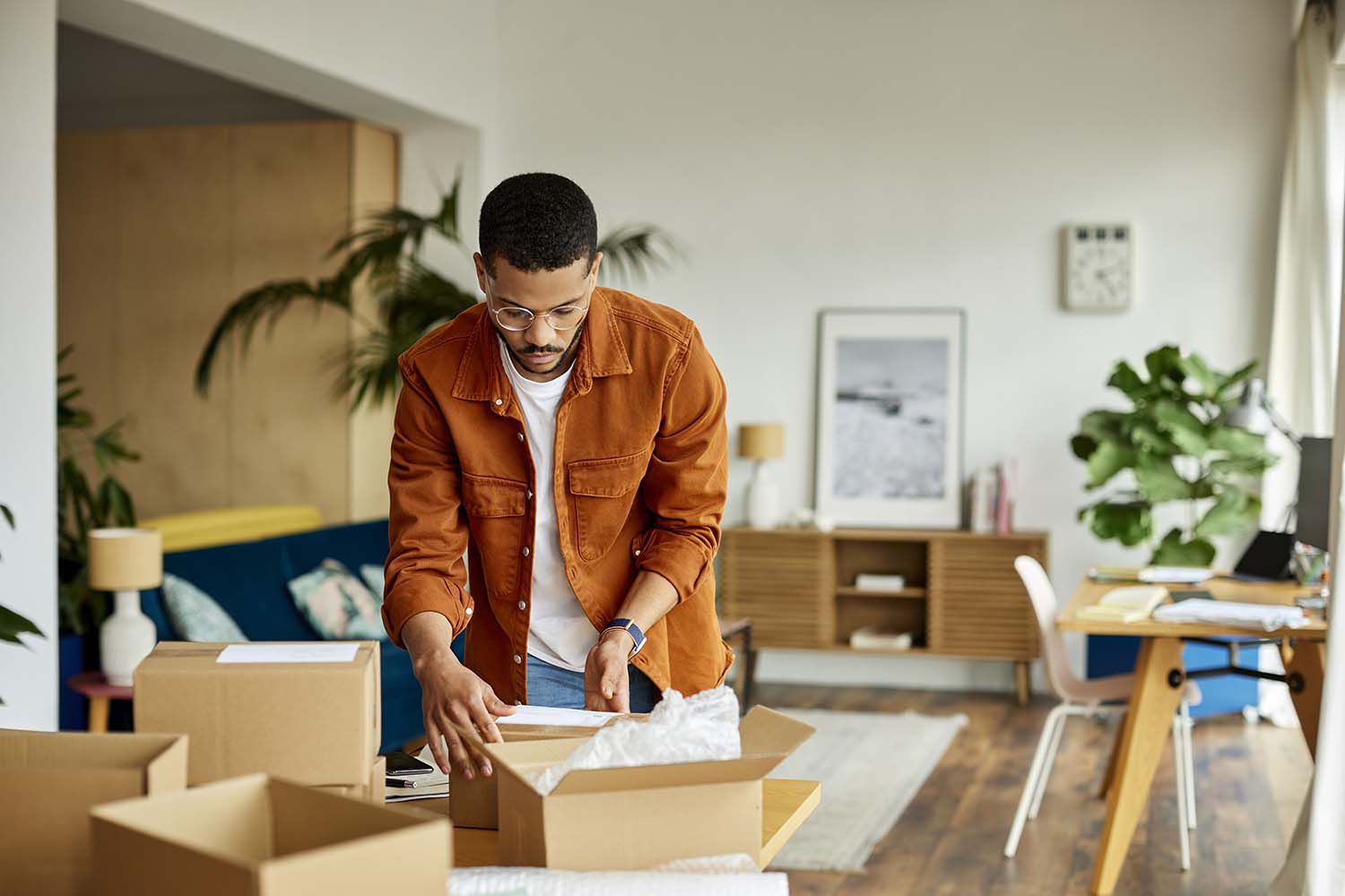 Young Businessman Packing Cardboard Box At Table in home