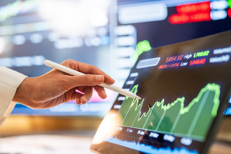 Close-up of a hand using a stylus to analyze financial trends on a tablet.