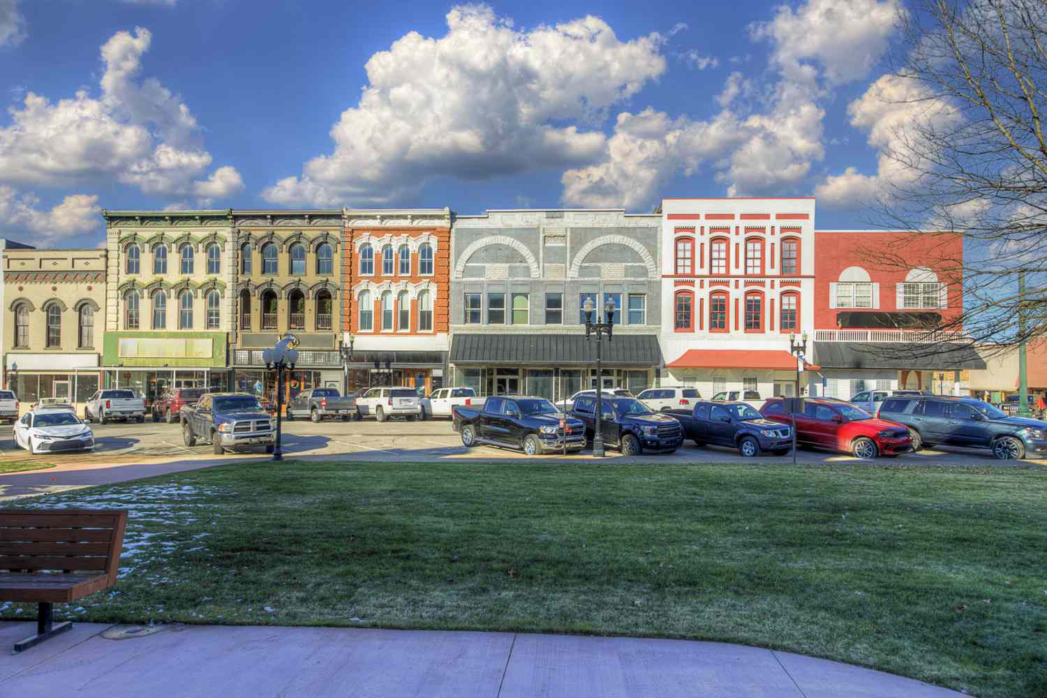 A row of colorful historic buildings lines a street, with various shops and businesses visible. Town Square, Paris, Tennessee.