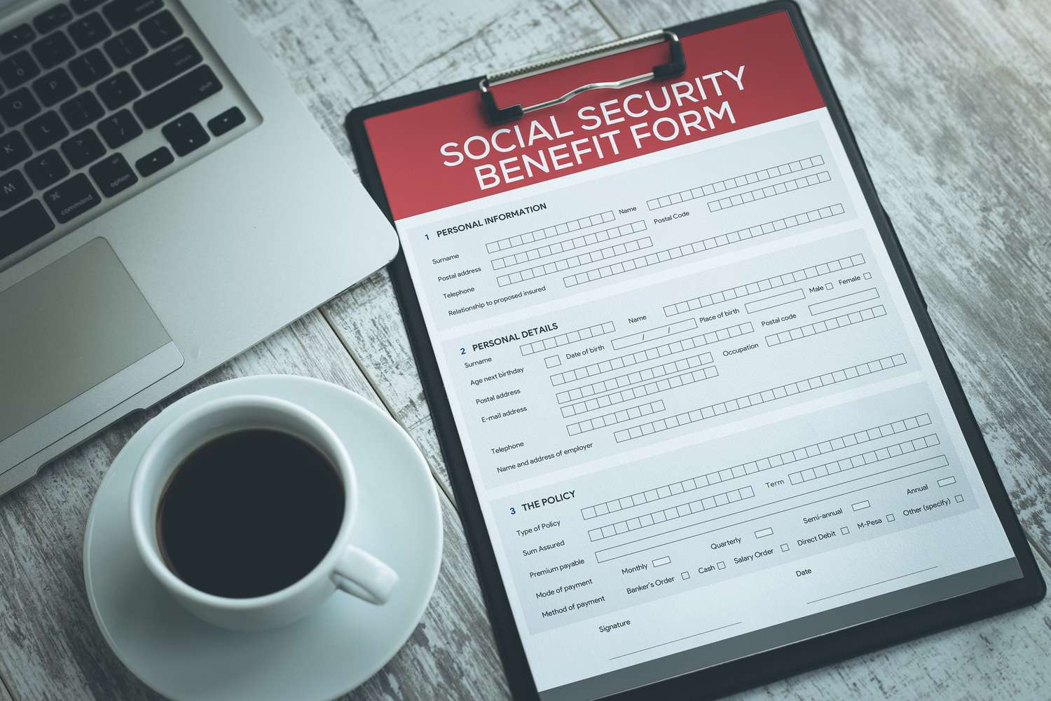 A social security benefit form on the desk, with a computer and a coffee cup.
