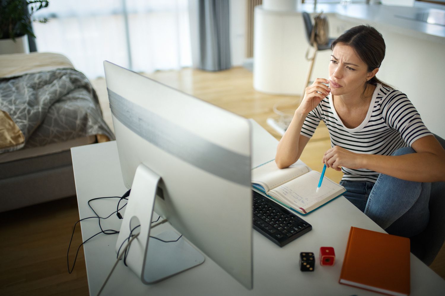 Closeup side view of an early 30's woman taking an online learning course. She's seated at a desk in her bedroom.