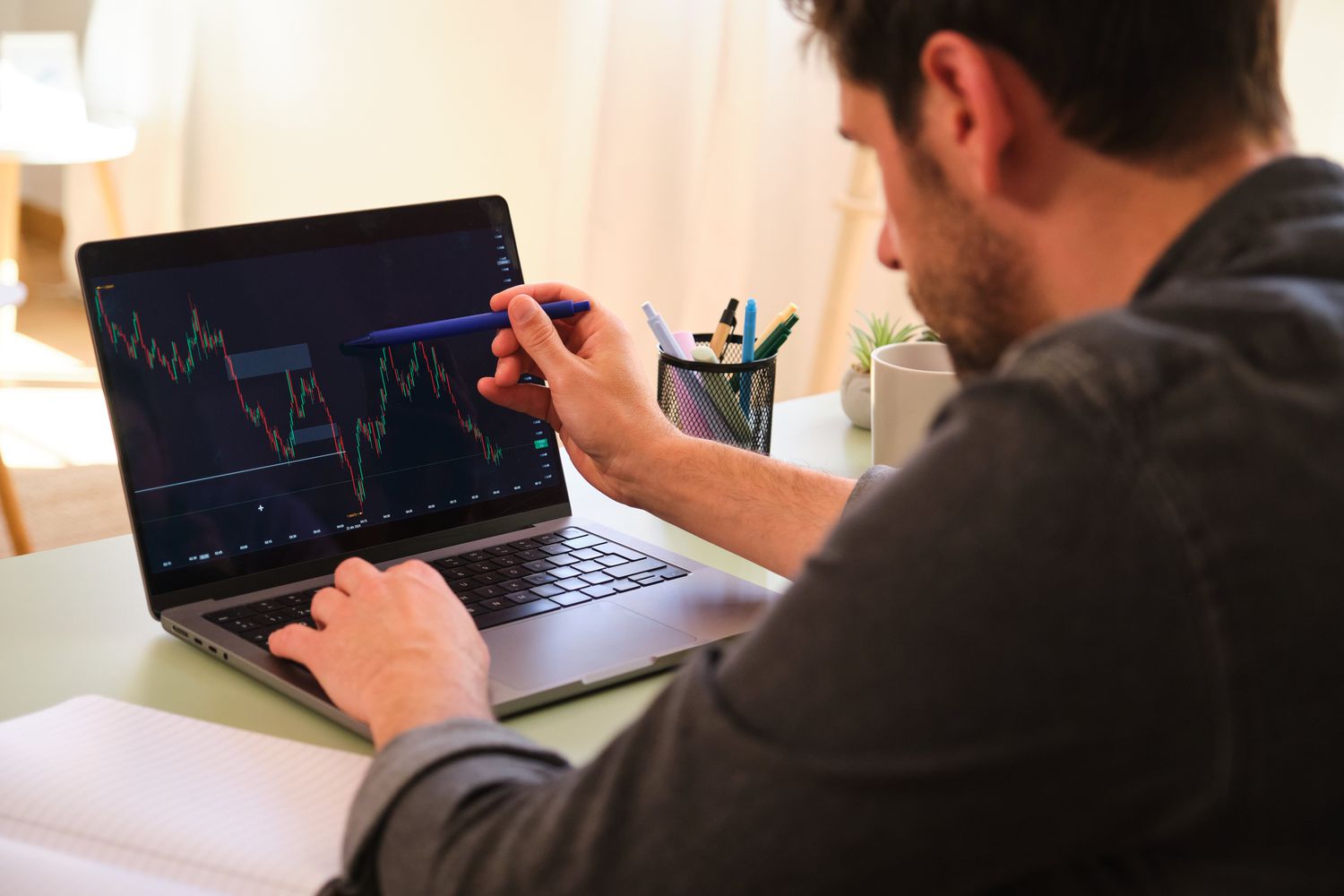 A trader uses a laptop showing a stock chart to identify price points showing support and resistance levels on the stock.