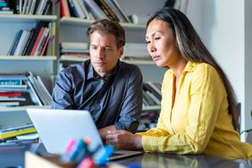 COuple in their 30s or 40s at hone, looking seriously together at a laptop