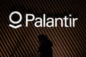 A person walks by a Palantir logo.