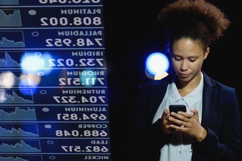 Person checking her phone at night with the photo overlaid against a ticker screen