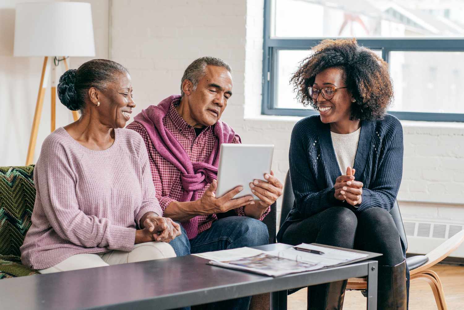 A couple sitting on a couch, talking with their female financial advisor