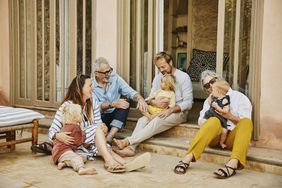 A group of people on a patio, sitting and holding young children