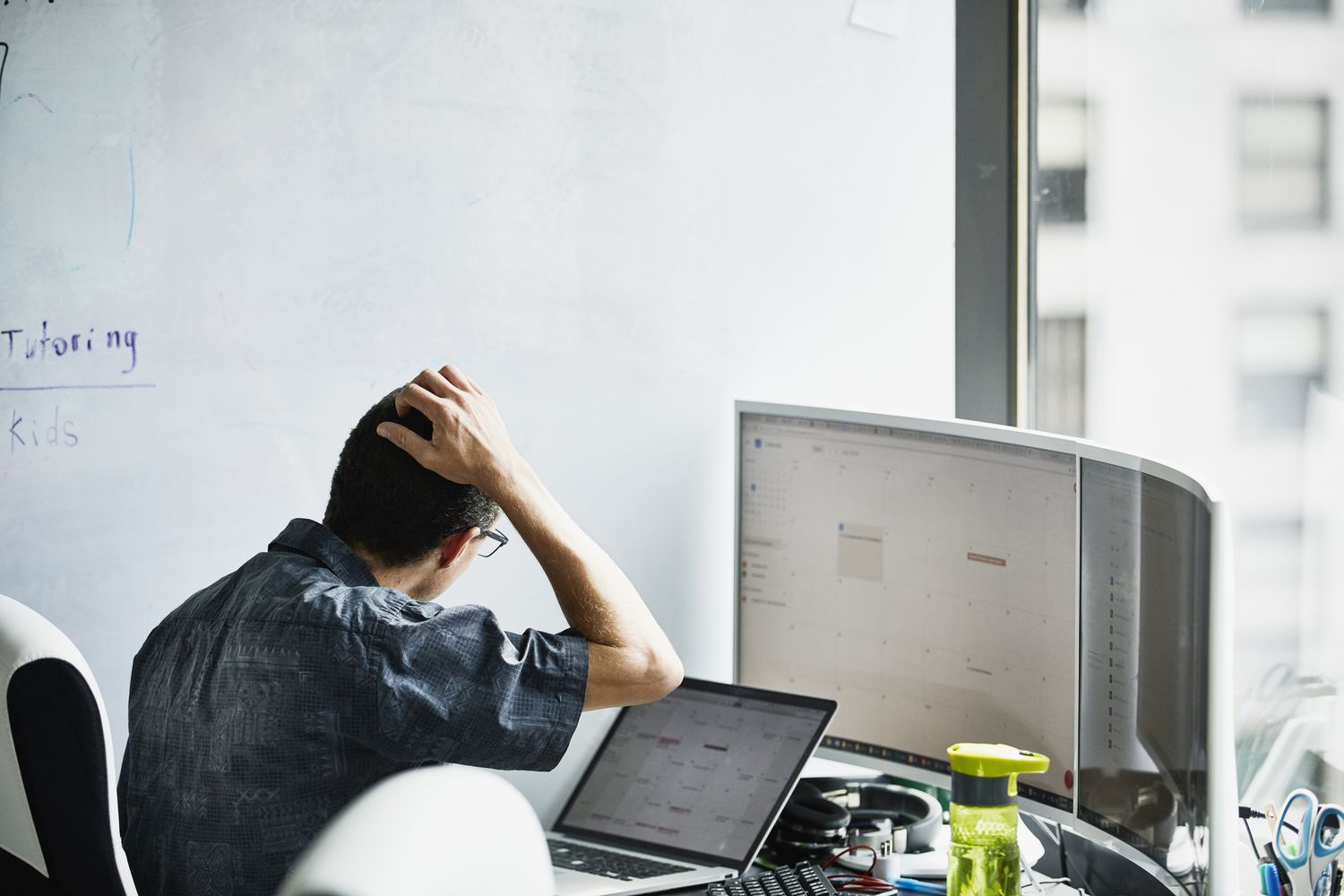 Engineer scratching head while looking at calendar on computer monitor.
