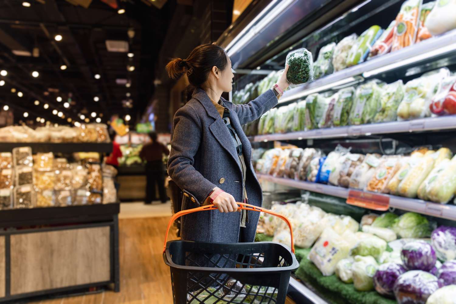 Woman picking out vegetables in a grocery store.